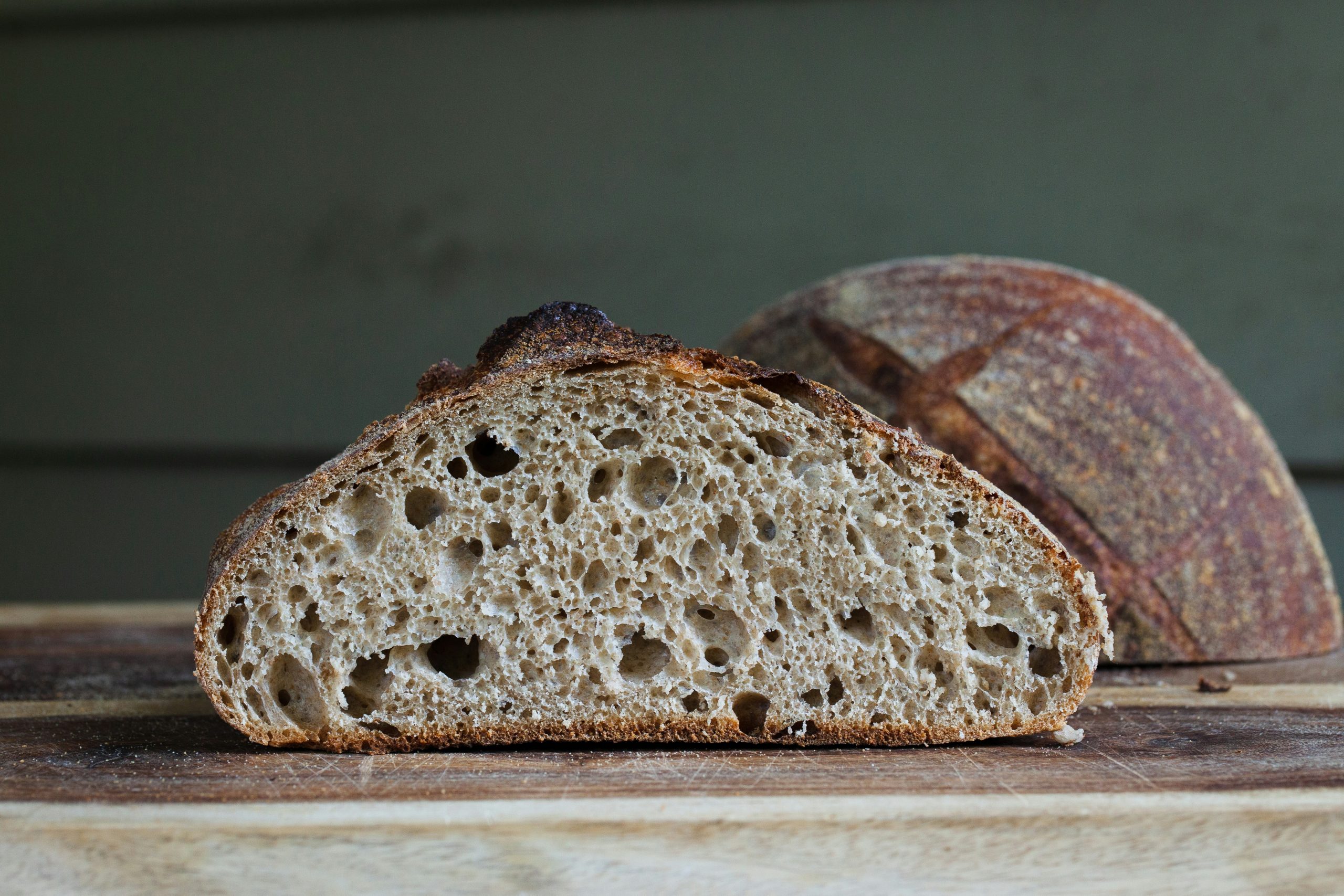  freshly baked loaf of sourdough bread, cut in half to reveal its soft, airy texture and golden crust.